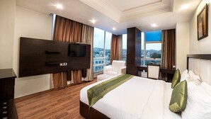 A hotel room with a large bed, a flat-screen TV, a desk, and a chair.