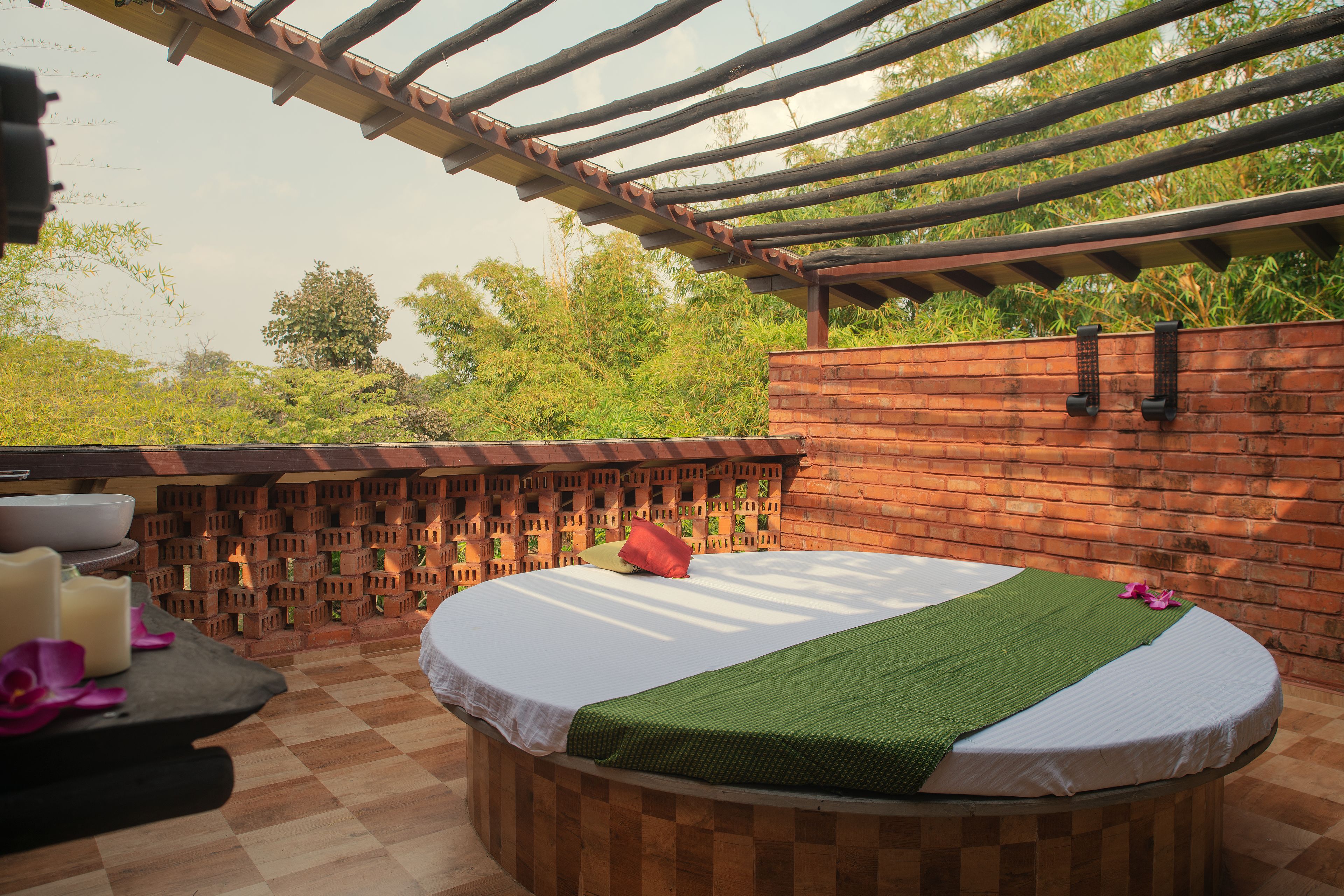 A spa room with a wooden bench, a massage table, and a brick wall.