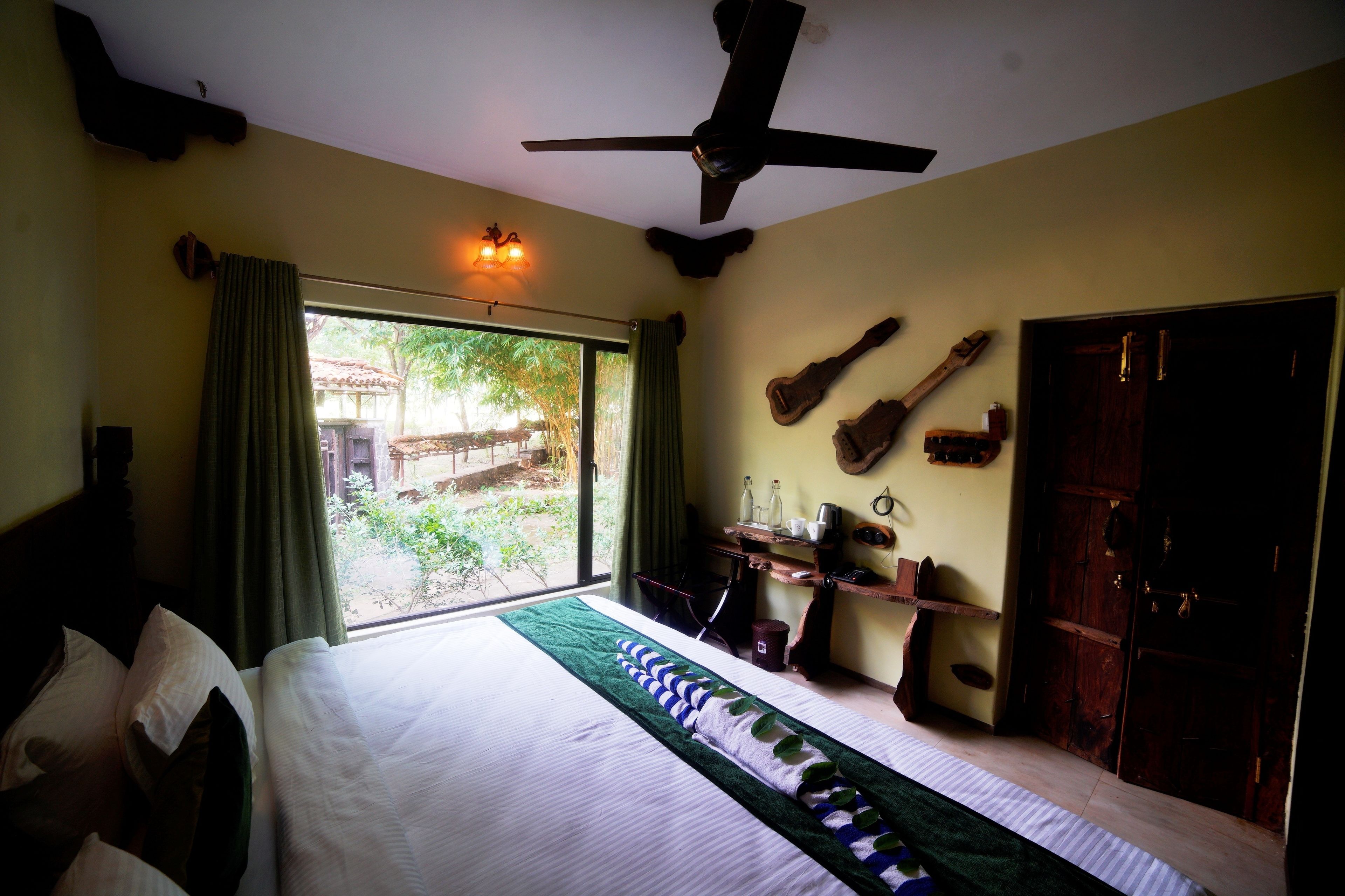 A bedroom with a bed, a ceiling fan, a window with curtains, and a view of the outdoors.