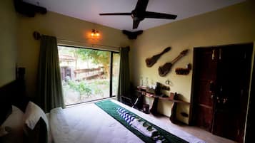 A bedroom with a bed, a ceiling fan, a window with curtains, and a view of the outdoors.