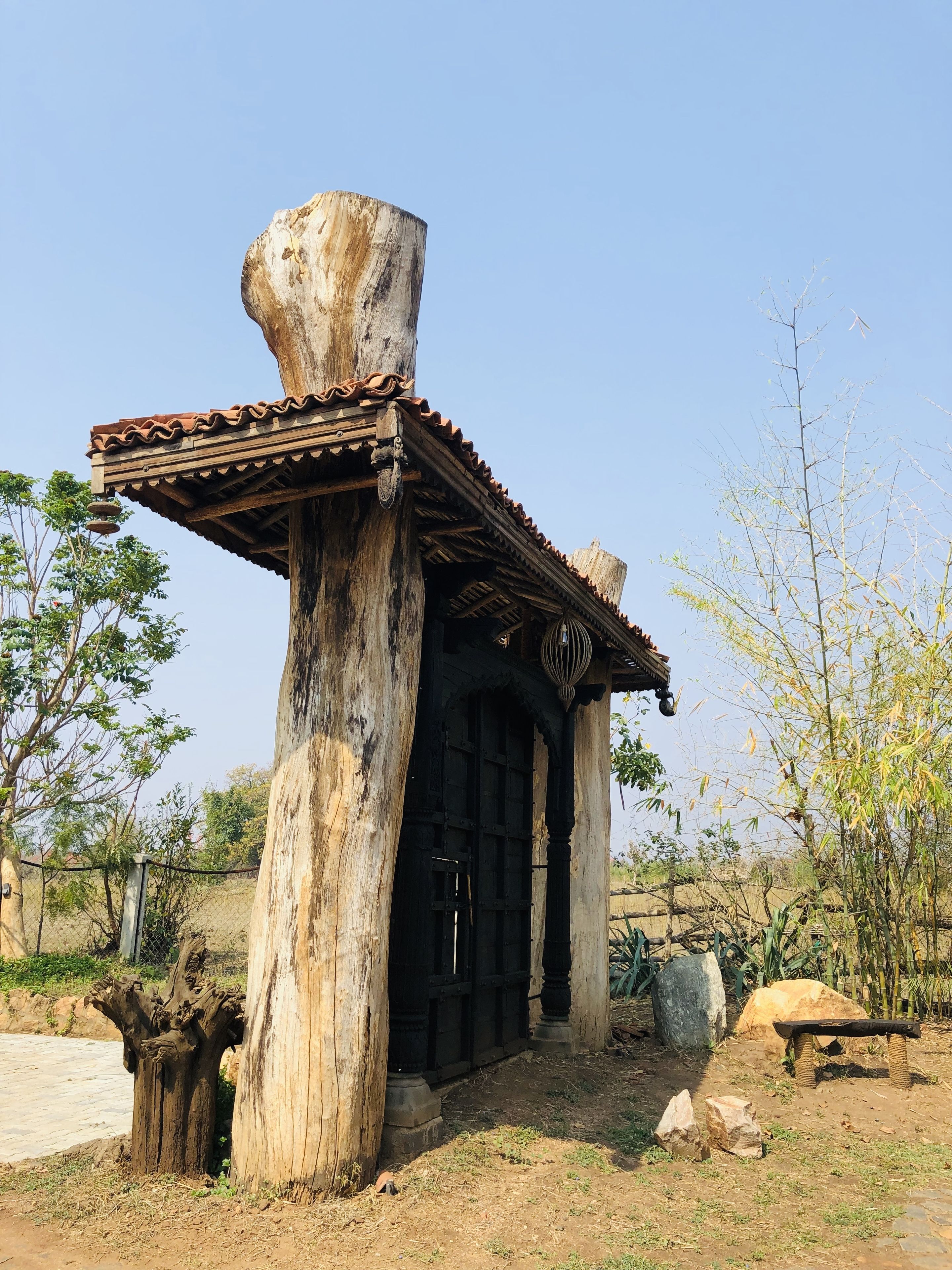 A rustic wooden structure with a tiled roof and a large tree trunk supporting it.