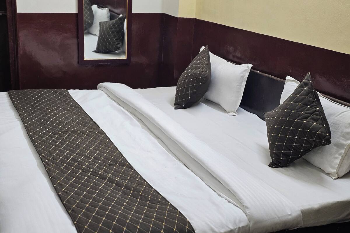 A neatly made bed with a quilted headboard, white linens, and patterned pillows.