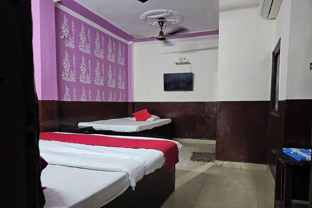 A hotel room with two beds, a ceiling fan, a TV, and a small table.