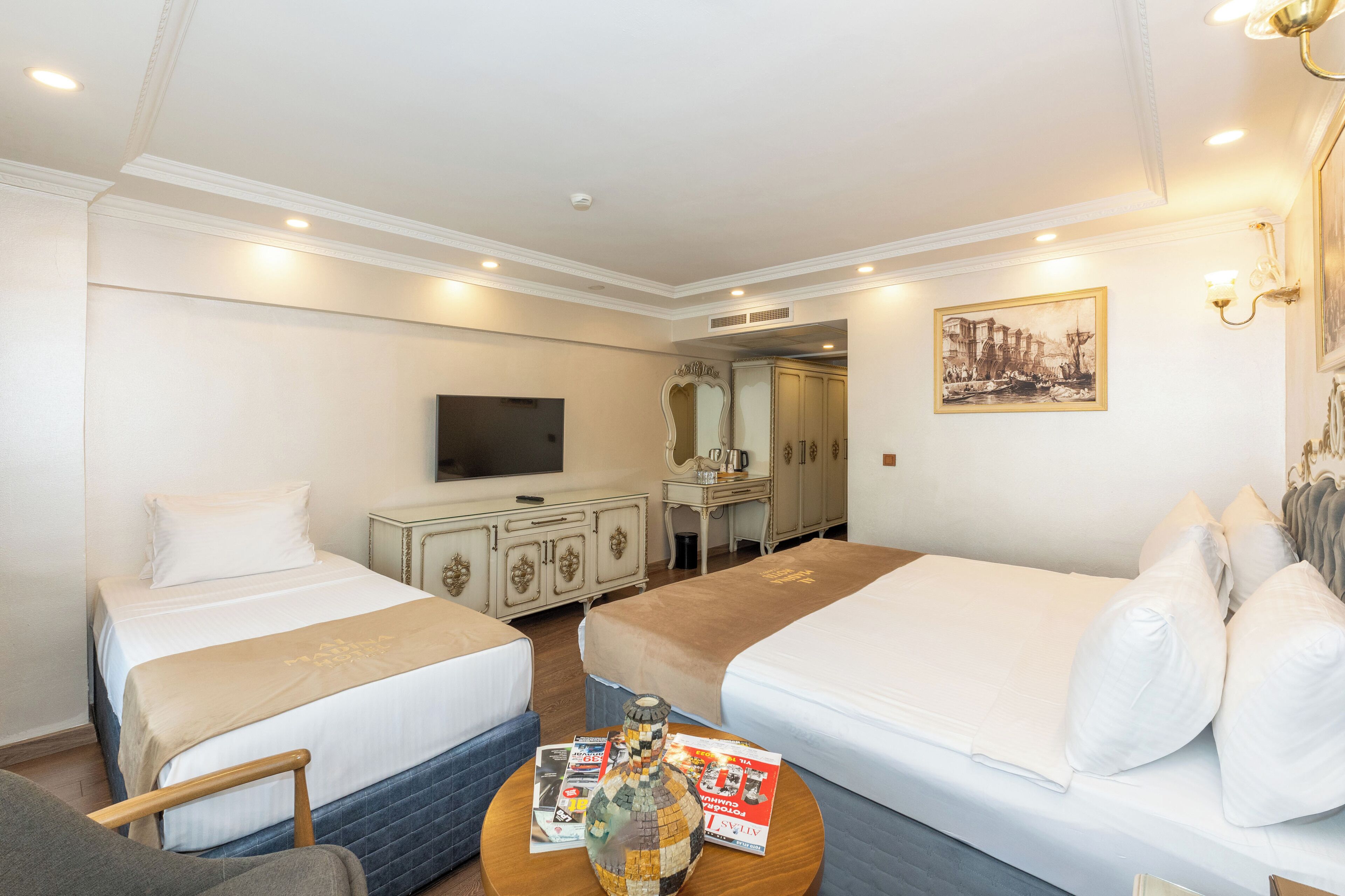 A hotel room with two beds, a TV, a dresser, and a mirror.