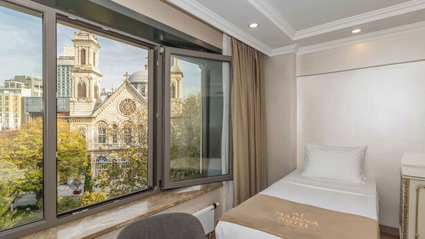 A hotel room with a large window offering a view of a historic building and trees. - Al Madina Hotel İstanbul (Istanbul)
