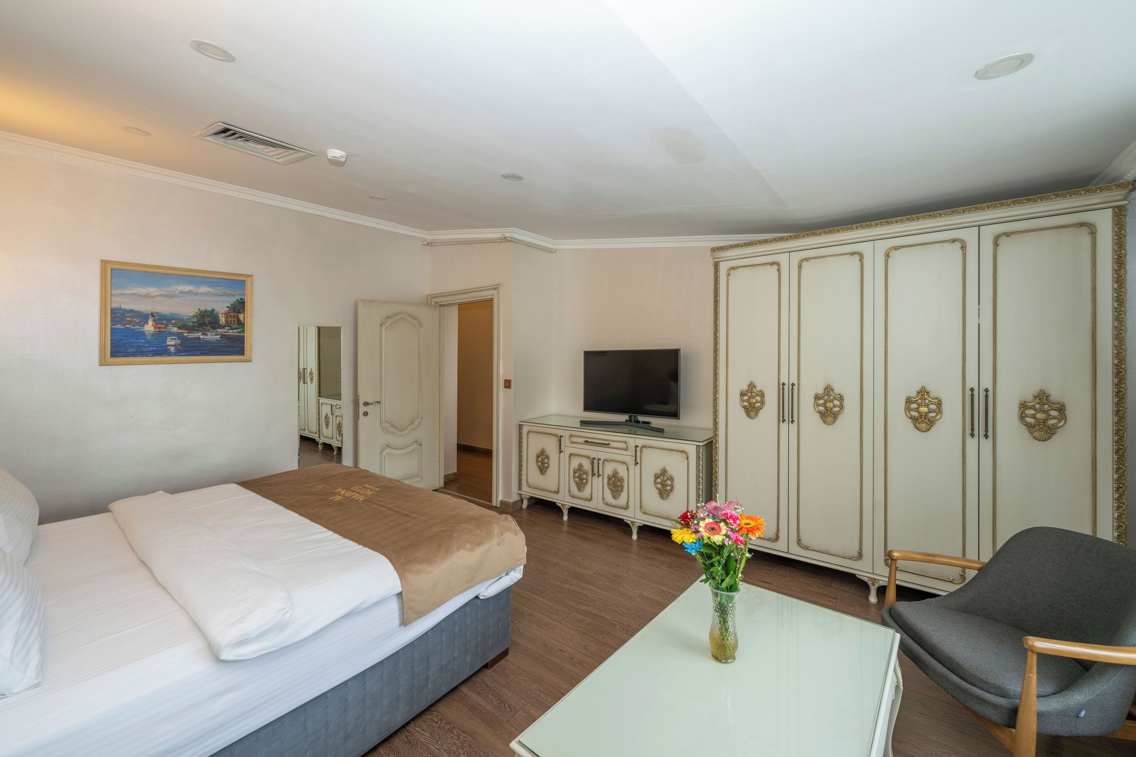 A hotel room with a bed, a TV, a dresser, and a wardrobe.