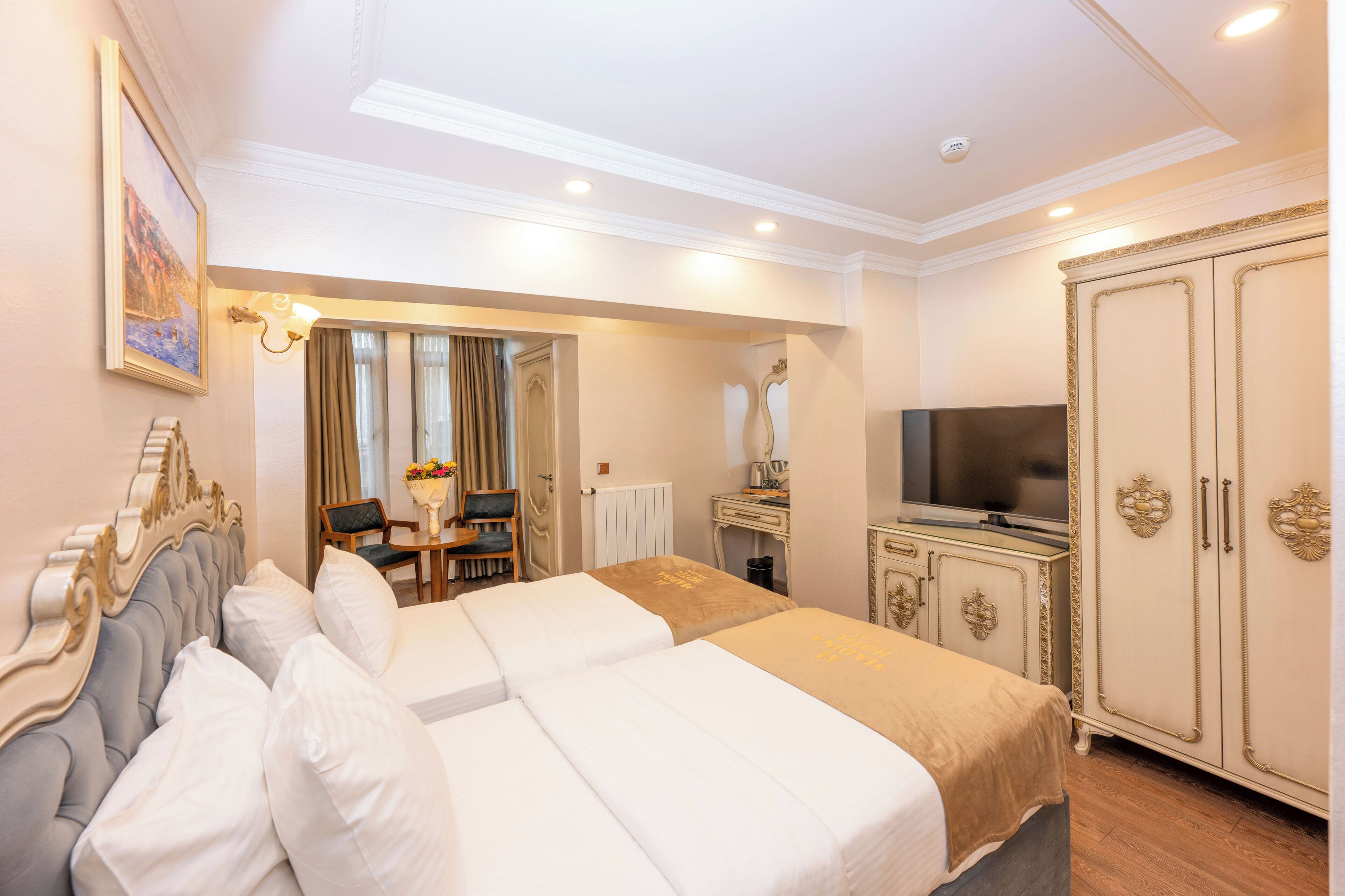 Une chambre d’hôtel avec un grand lit, une télévision, une armoire et un bureau avec une chaise.
