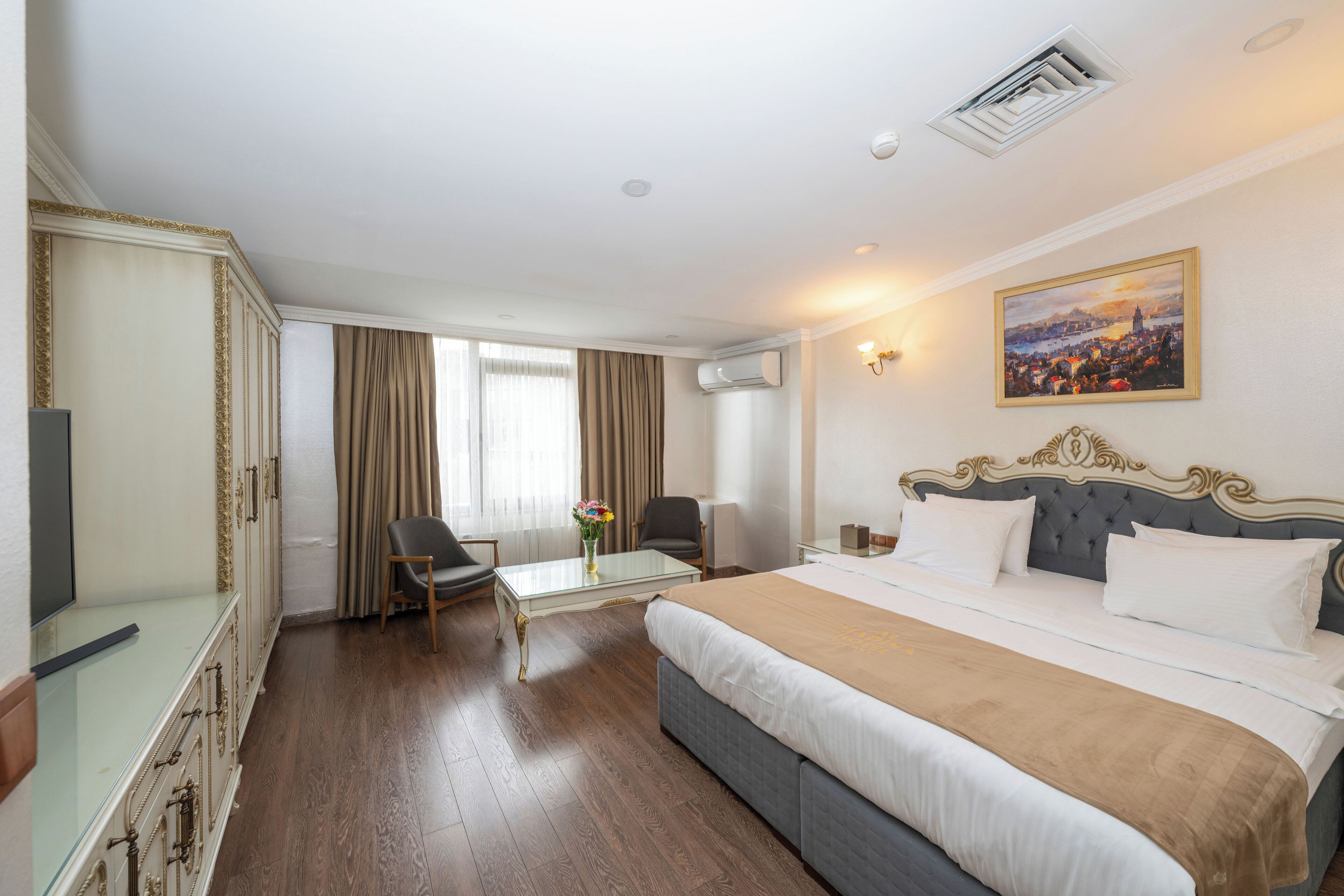 A hotel room with a large bed, a desk, a chair, and a television.