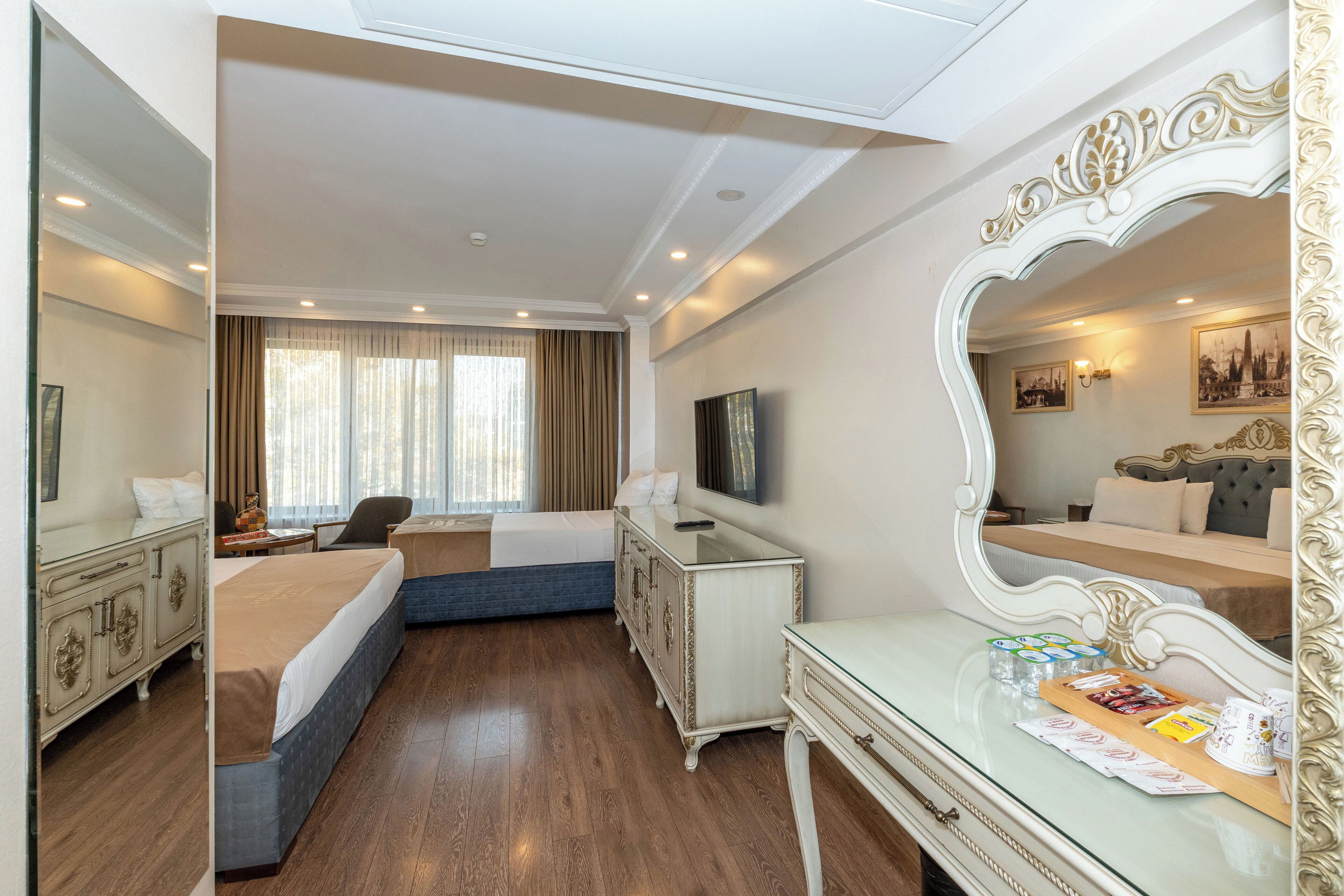 A hotel room with a bed, a desk, a dresser, a mirror, and a television.