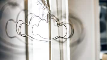 A close-up of a metal cloud-shaped decoration hanging from a vertical structure.