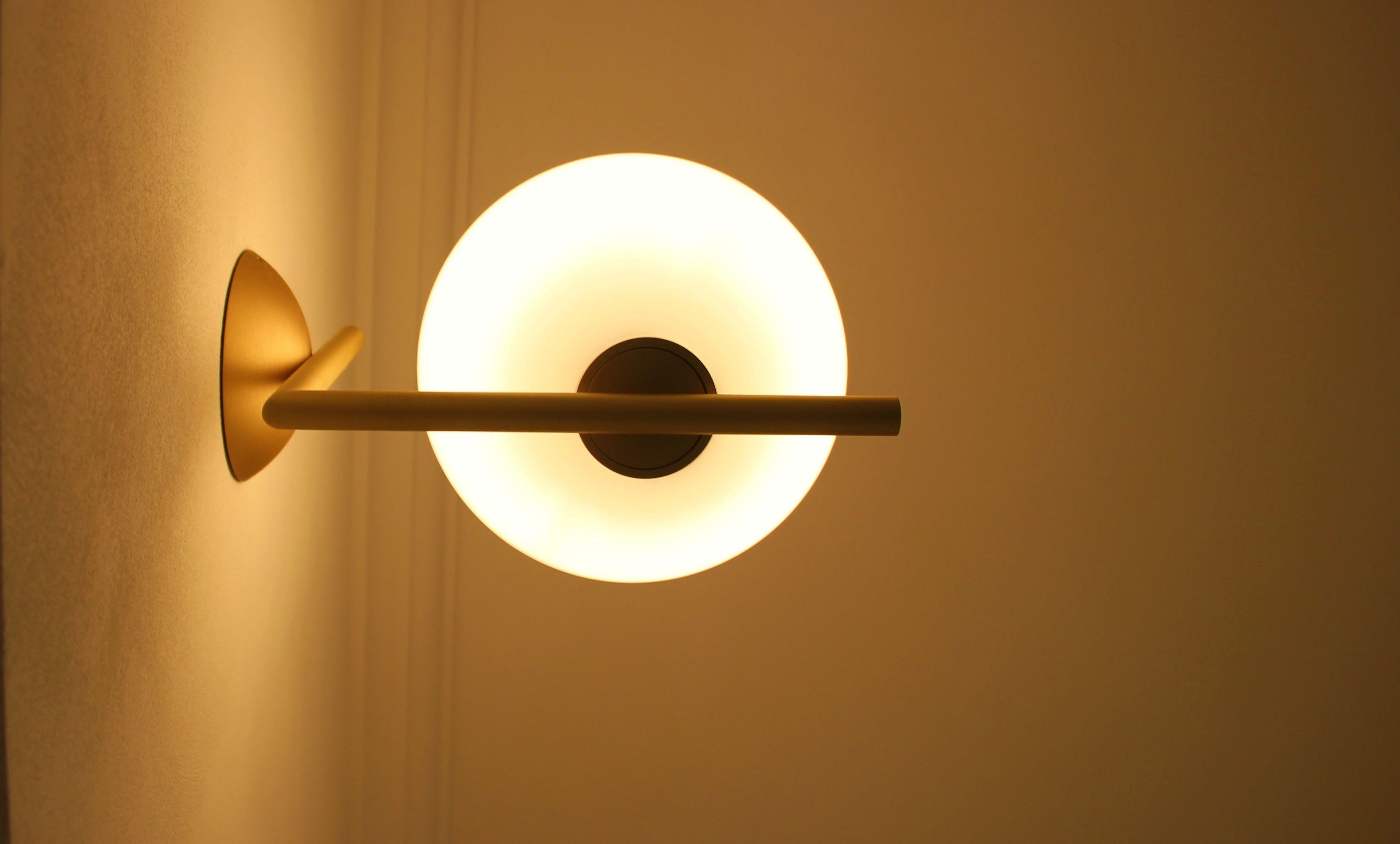 A wall-mounted light fixture with a circular design and a central dark circle.