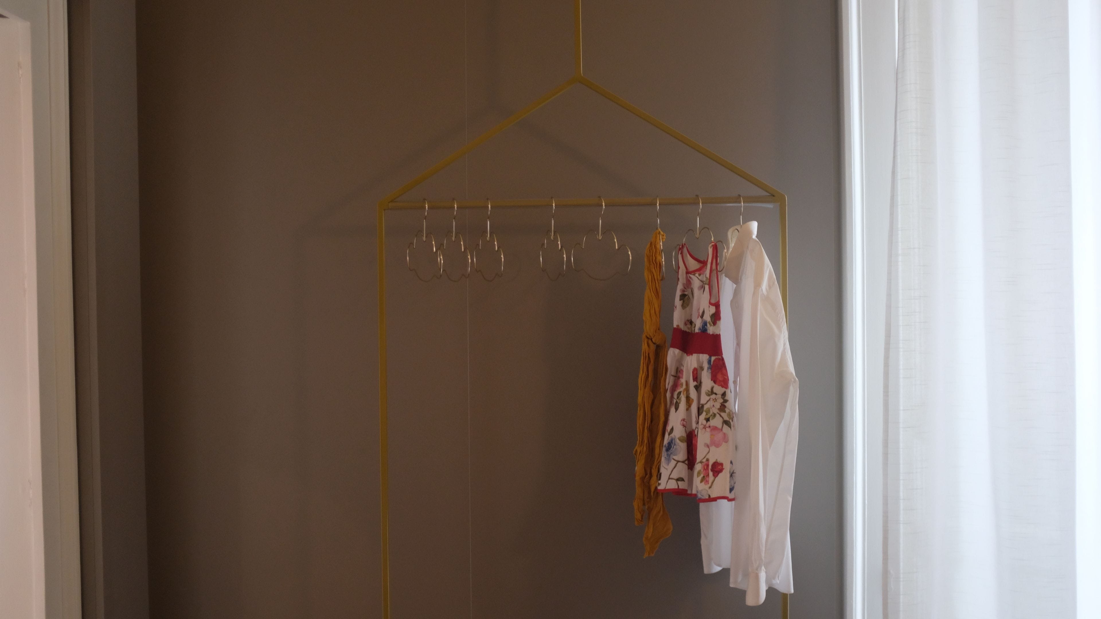 A room with a hanging clothes rack against a wall.