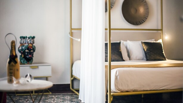 A room with a bed, a small table, and a decorative statue. - Scene Suites Apartments (Catania)