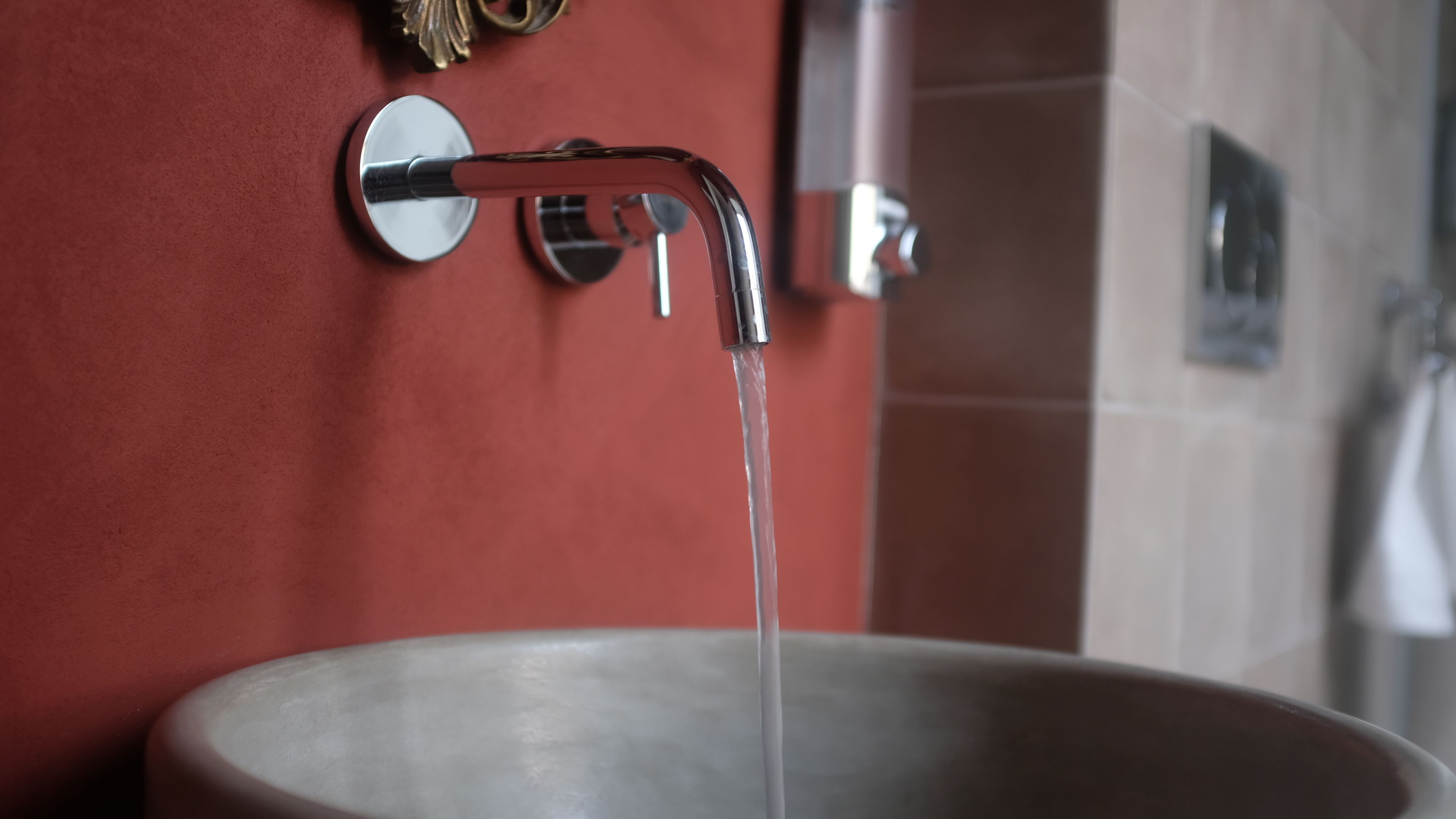 A bathroom sink with running water, a mirror, and a towel rack.