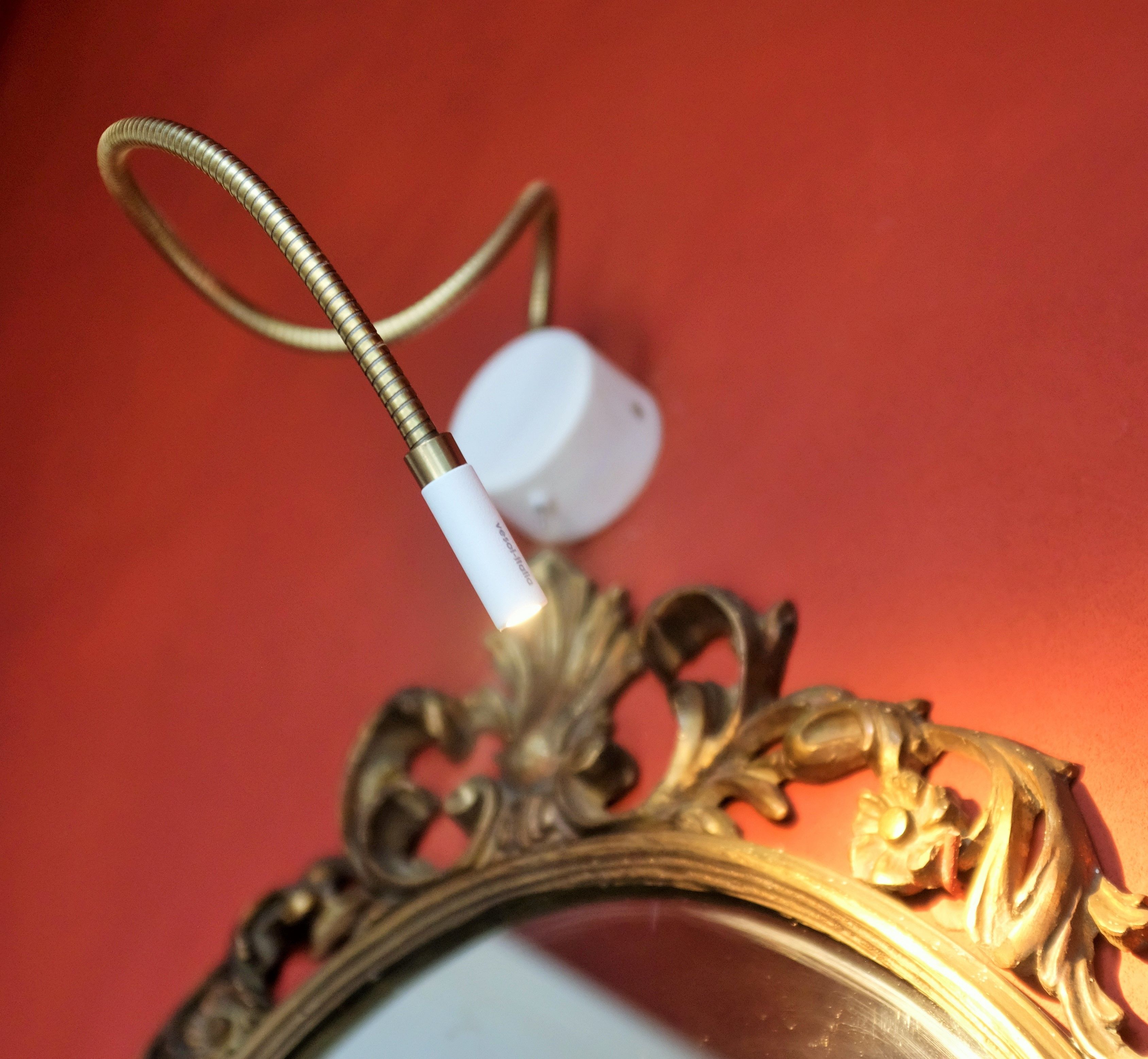 A close-up of a decorative mirror with an ornate frame, a cord, and a white object attached to it.