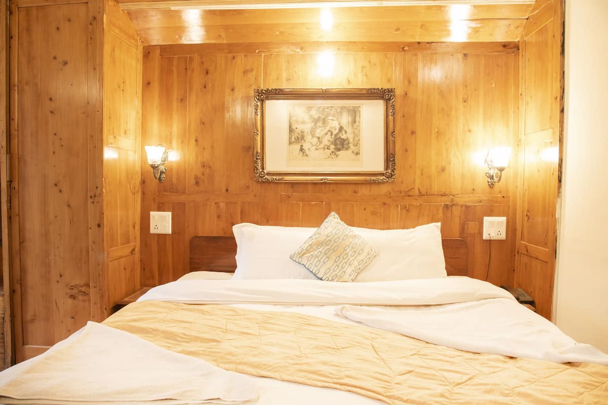 A wooden-paneled room with a bed, two wall-mounted light fixtures, and a framed picture on the wall.