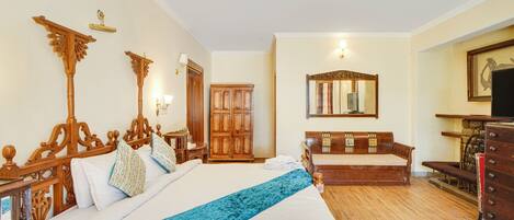 A hotel room with a large bed, wooden headboard, a wardrobe, a mirror, and a television.