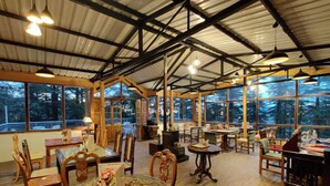A spacious room with large windows, wooden furniture, and a high ceiling with metal beams. - Shimla British Resort (Shimla)