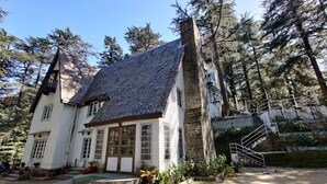 A rustic house with a steeply pitched roof, surrounded by dense forest. - Shimla British Resort (Shimla)