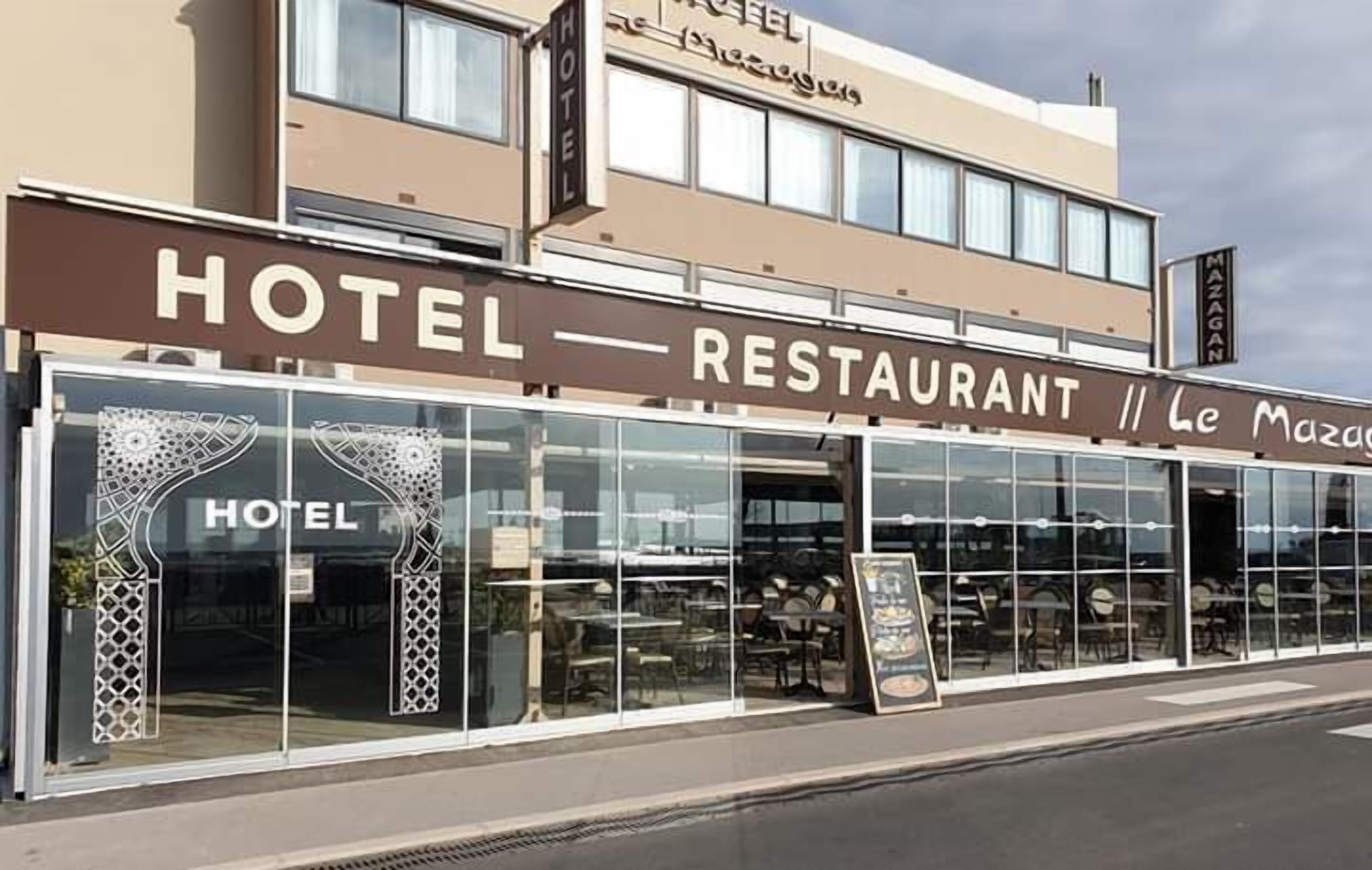 A building with a sign that reads "HOTEL RESTAURANT Le Mazagan".