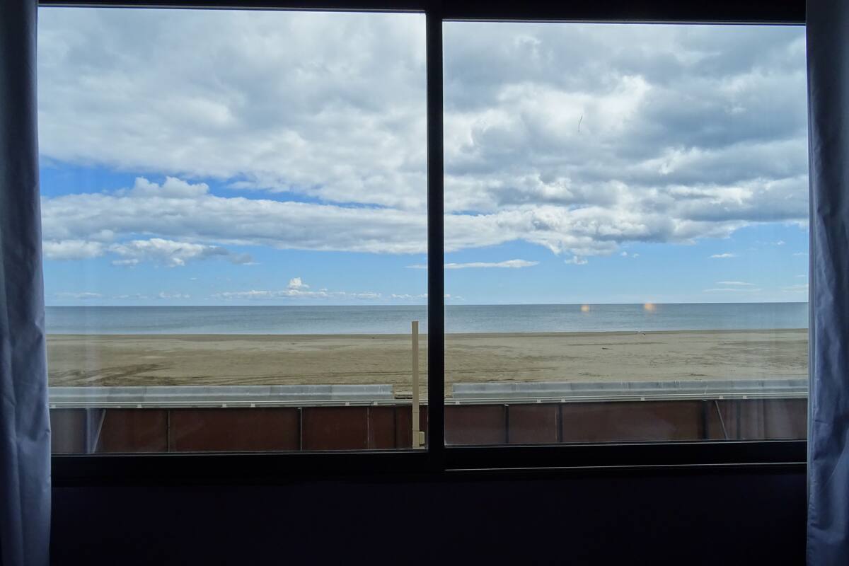 Ein Zimmer mit einem großen Fenster mit Blick auf einen Strand.