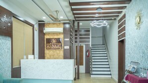 Zona reception di un hotel, con scrivania, insegna dell'hotel, una scala e un estintore.