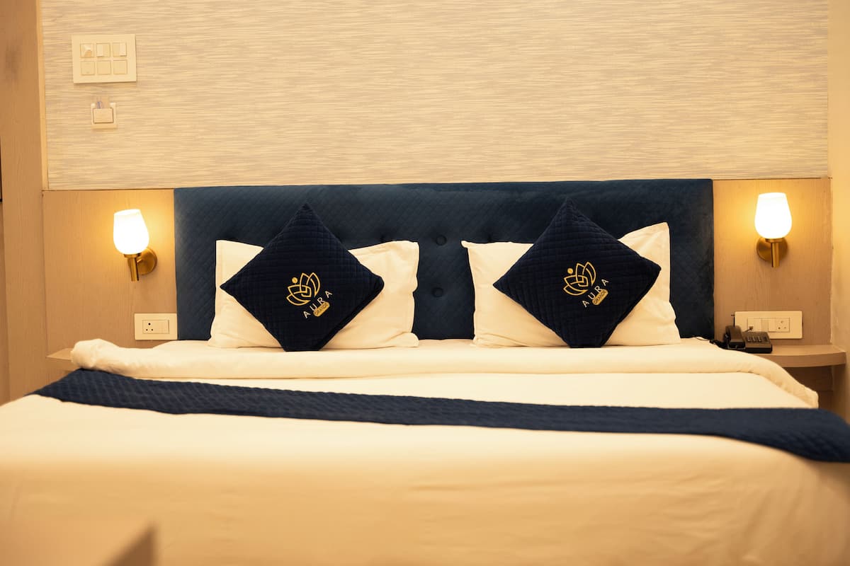 Una camera d'albergo con un letto, due lampade da comodino e un comodino con un telefono.