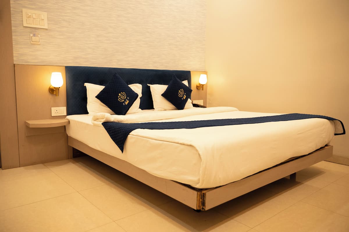Un letto rifatto con cura, una testiera scura, due abat-jour e un comodino in legno.