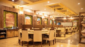 Un ristorante con diversi tavoli e sedie, un bancone con vetrina e decorazioni murali.