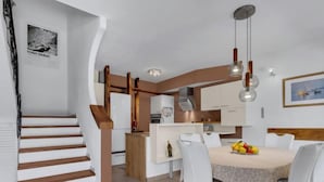 A modern kitchen with white cabinets, a central island, and a dining area with a round table and chairs. - Marijan by Interhome (Brač/Sutivan)