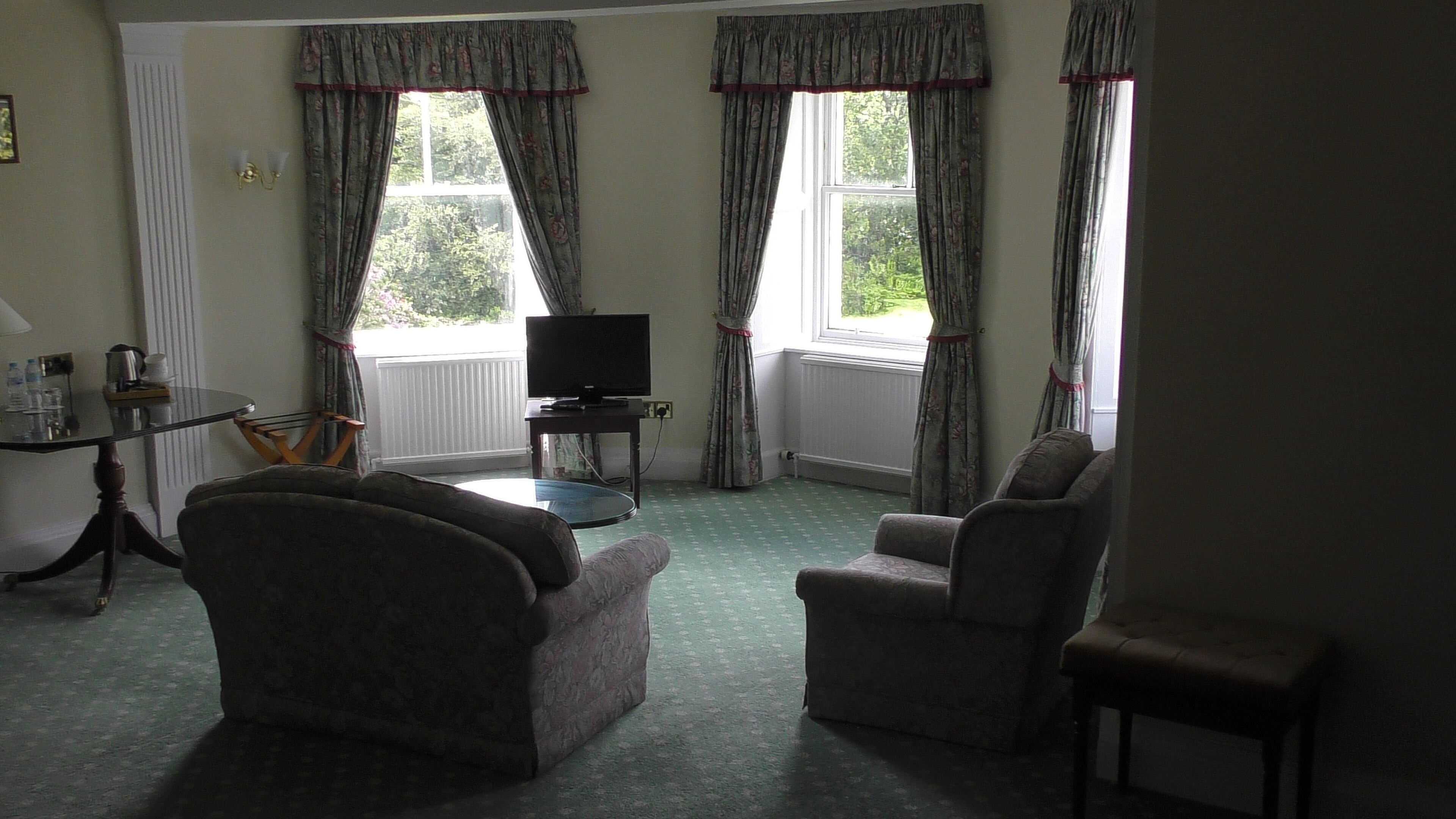 A living room with two armchairs, a television, and a small table.