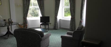 A living room with two armchairs, a television, and a small table.