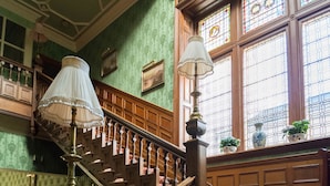 A grand staircase with ornate railings and a chandelier, leading to a landing with a red patterned carpet. - Kirroughtree Country House B&B (Newton Stewart)
