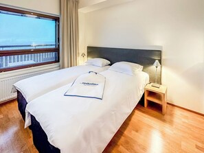 A hotel room with a large bed, a bedside table, a lamp, and a window with curtains. - Ski chalets 6203 by Interhome (Ylläsjärvi)