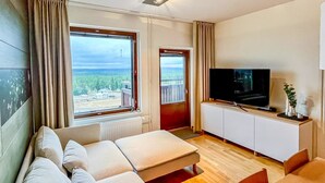 Hotelkamer met slaapbank, televisie, een klein tafeltje en uitzicht op de omgeving.