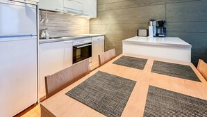 Een moderne keuken met witte kastjes, een inbouwoven en een koffieapparaat.
