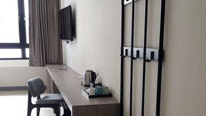 Una habitación pequeña y moderna con escritorio, silla y televisor en la pared.