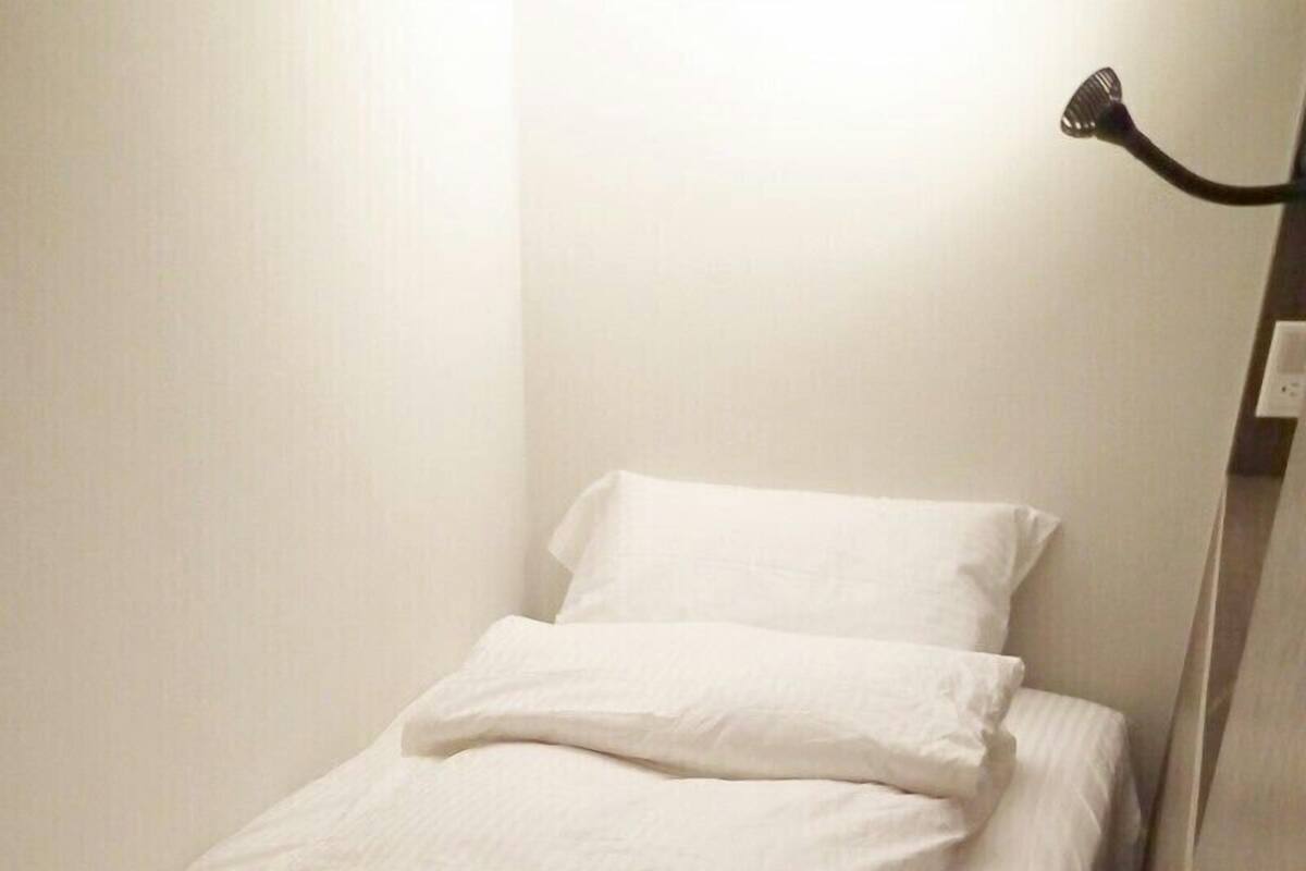 A neatly made bed with white linens in a hotel room.