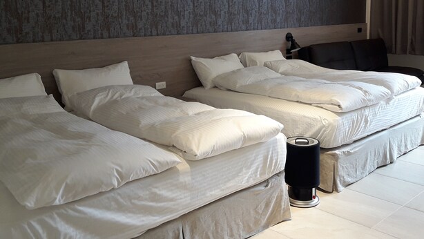 Una habitación de hotel con dos camas, un cabecero, una lámpara y una cortina.