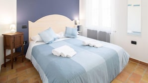 Une chambre à coucher comprenant un lit, des tables de chevet, une commode, une fenêtre et un miroir fixé au mur.