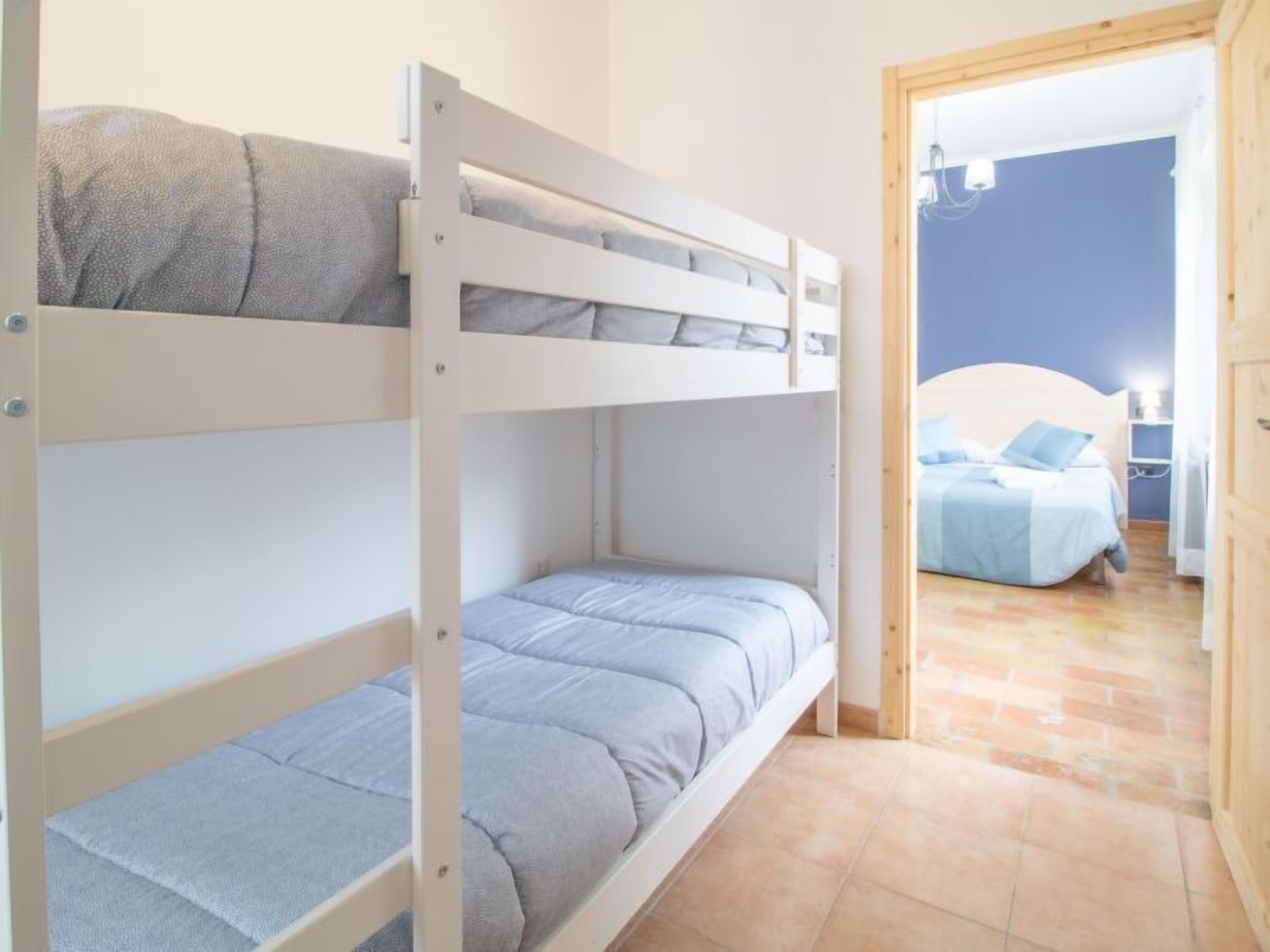 Une chambre avec un lit superposé, le lit du bas étant visible, et un lit séparé à l’arrière-plan.