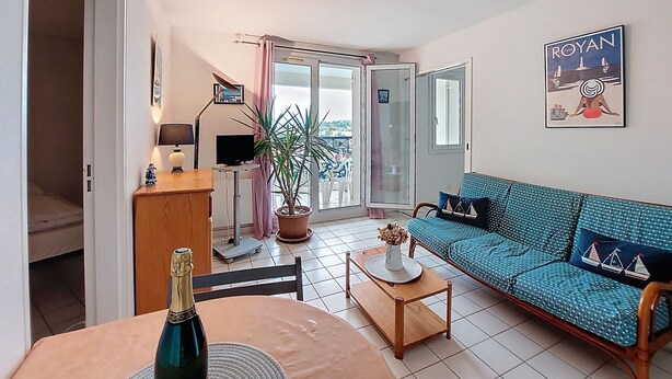 Una sala de estar con sofá, mesa de centro, televisor y balcón con vistas.
