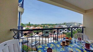 Un balcón con una mesa dispuesta para dos, con vista a una zona residencial.