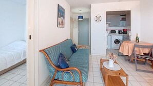 Un espacio habitable pequeño con un sofá, una mesita de comedor y una kitchenette.