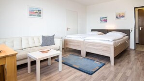 Una habitación moderna y bien iluminada con una cama, un sofá, una mesita y una puerta.