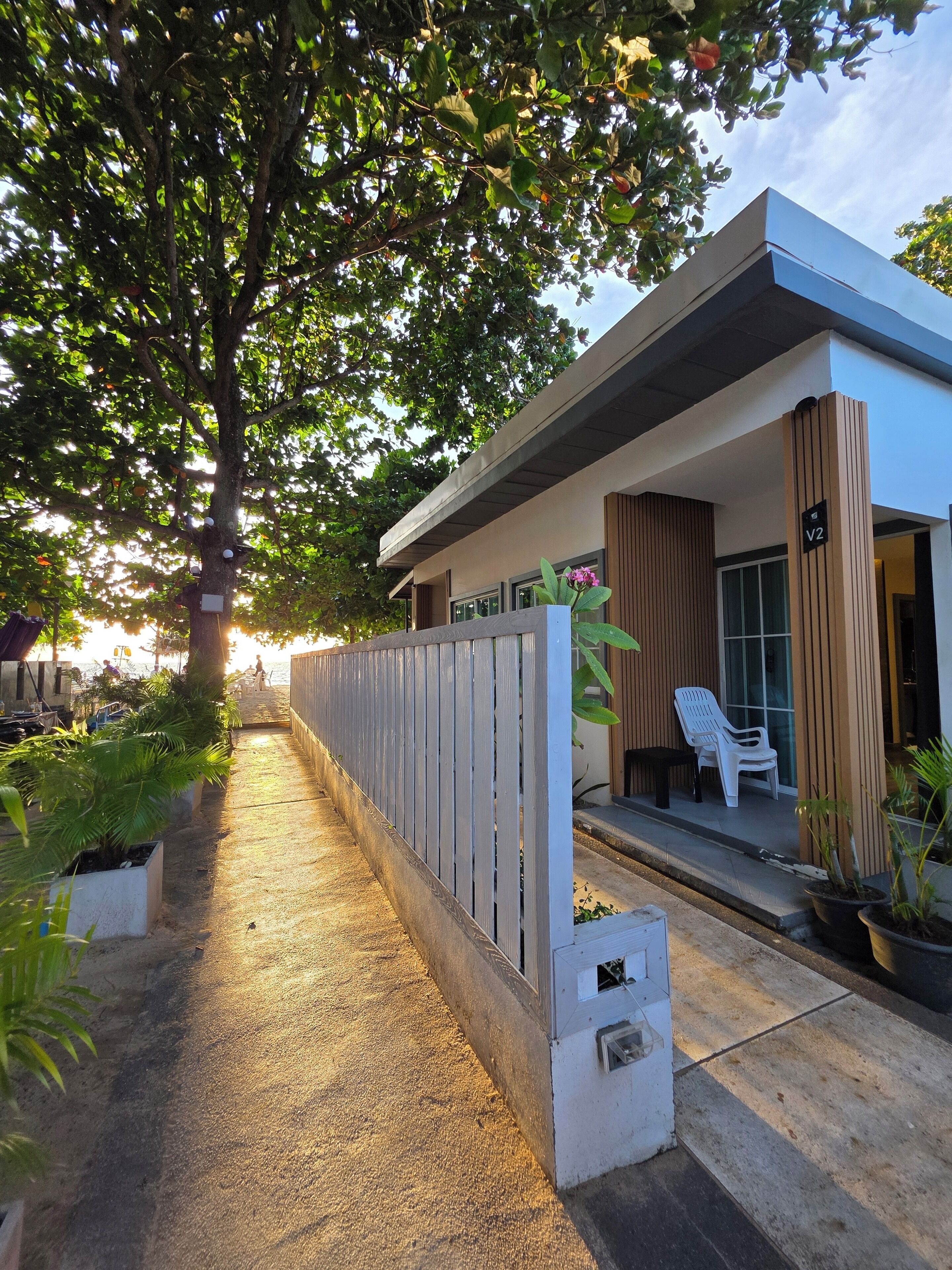 A modern building with a covered porch, a wooden fence, and potted plants.