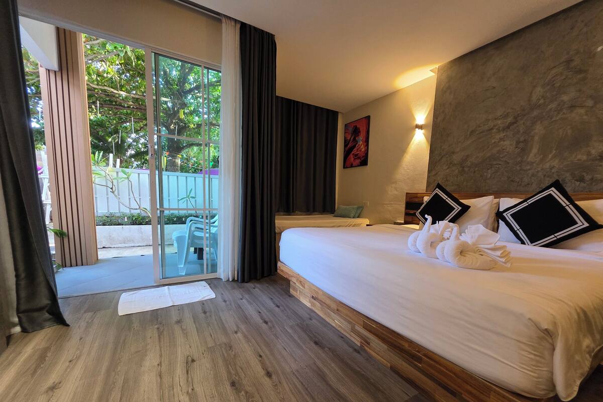 Ein Hotelzimmer mit einem großen Bett, Holzboden, einer Schiebeglasdoor zum Balkon und einem Bild an der Wand.