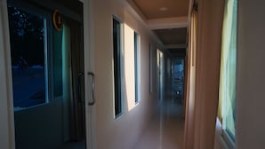 Corredor de hotel com um sinal de número 1, várias janelas e uma porta com puxador.