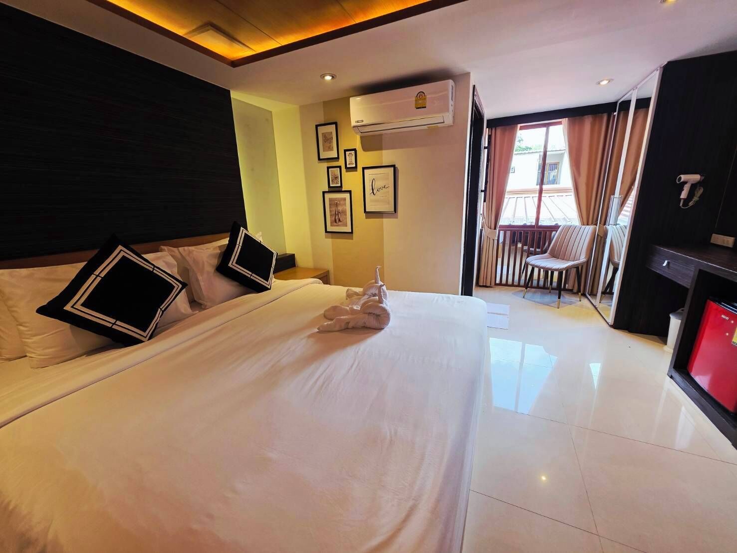 Una camera d'albergo con un letto grande, una scrivania, un condizionatore e un balcone con una sedia.