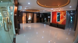 Um hall amplo com piso lustroso, um balcão de recepção e uma parede de destaque em vermelho.